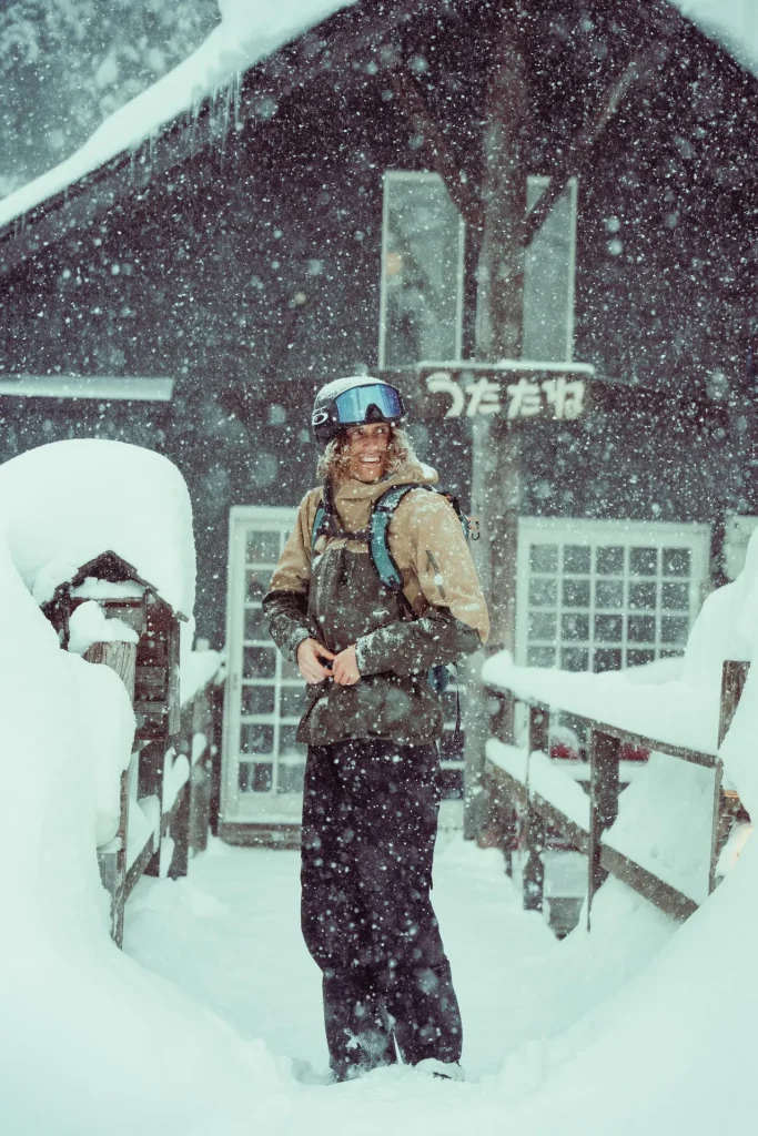 Skier smiling in heavy snowfall outside a Myoko Kogen ski lodge, Escape Myoko